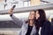 Businesswomen Commuting To Work Waiting For Train On Station Platform Taking Selfie On Mobile Phone