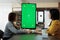 Businesswomen looking at green screen chroma key mock up vertical monitor