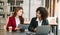 Businesswomen work and discuss their business plans. A Human employee explains and shows her colleague the results paper in modern