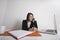 Businesswomen writing notes while using cell phone at office desk