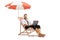 Bussinesman sitting on a deck chair under umbrella and using a laptop computer