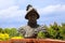 A bust statue of a Spanish explorer on the Savannah riverfront surrounded by red brick and lush green plants and yellow flowers