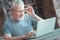 Busy aged man touching his glasses looking at the screen.