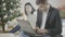 Busy concentrated businessman typing on laptop keyboard with sad blurred woman sitting at Christmas tree at background