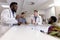 Busy diverse doctors and medical staff talking at reception desk of hospital ward, copy space