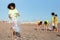 Busy diverse teenager people in uniform and black curly girl collect garbage and plastic bottles in bag on beach