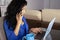 Busy executive talking on the phone with her work group, dressed in blue in commemoration of Blue Monday and happy with her laptop