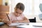 Busy little girl writing in notebook, preparing school homework