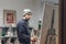 Busy man artist with a brush in his hand picks up an oil painting in a cozy studio. Talented young painter paints a painting on