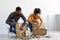 Busy millennial african american husband and wife preparing for move, stack cardboard boxes for things