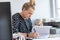 A busy office woman eats ice cream at her workplace without interrupting work