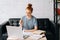 Busy pretty redhead young woman student is taking notes in workbook by looking at laptop screen.