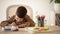 Busy serious european small kid drawing, writing, studying at table in living room