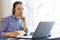 Busy serious Millennial girl, woman in headphones working at laptop