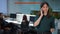 Busy serious young woman talking on phone standing in office with blurred coworkers chatting sitting at computers at