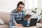 Busy smart millennial european male student in domestic clothes with stubble in glasses with book and pc