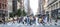 Busy street scene in New York City with groups of people walking across a crowded intersection on Fifth Avenue in Midtown