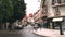 A busy street in a small Spanish town where people walk and cars drive.