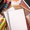 Busy students desk with blank folded notebook