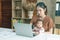 Busy woman trying to work while babysitting newborn baby daughte.  Young beautiful Asian mother holding little baby on lap while
