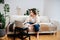 Busy young woman holding embroidering loop, watching instructions on laptop