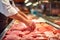 Butcher arranging fresh chicken breasts at a meat counter, culinary selection in progress