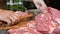 The butcher beats pieces of pork with a large hammer. The cook prepares the meat before cooking. A large mountain of