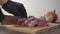 Butcher in black gloves cuts pork meat for goulash