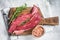 Butcher choise Bavette raw beef meat steak or flank flap on a wooden board with herbs. White background. Top view