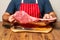 Butcher in classic red and white stripe apron holding fresh uncooked tomahawk steak. Prime cut of beef. Top quality product with