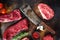 Butcher cleaver knife with set of different alternative types of raw beef steaks on a rustic metall background top view layflat