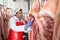 Butcher measuring temperature of raw pork carcasses in cold storage
