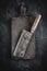 Butcher Meat Cleaver and Rustic Wood Chopping Board on Dark Background