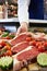 Butcher Showing Customer Sirloin Steak In Refrigerated Display