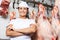 Butcher Standing Against Meat Hanging In Butchery