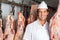 Butcher Standing Near Meat Hanging In Butchery