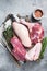 Butchered whole duck, raw breast steak, legs, wings on a butcher cutting board. Gray background. Top view