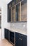 A butler\\\'s pantry with blue cabinets and a tiled backsplash.