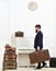 Butler and service concept. Macho attractive, elegant carries vintage suitcases, side view. Man with beard and mustache