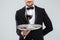 Butler in tuxedo holding silver tray with glass of wine