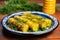 butter glazed sweet corn garnished with herbs on a vibrant ceramic plate