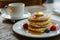 Butter and honey pancakes on elegant white plate, displayed on charming wooden table