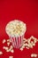 Butter popcorn in a red popcorn cup, snack in the house or cinema on a red background