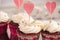 Buttercream cupcakes decorated with silver candies and paper hearts close-up.