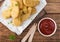 Buttered chicken nuggets on chopping board with wooden forks and ketchup on wooden background. Macro