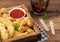 Buttered chicken nuggets and popcorn bites in vintage wooden box with ketchup and glass of cola on wooden background