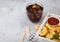 Buttered chicken nuggets and popcorn bites in white vintage wooden box with ketchup and glass of cola on light background. Space