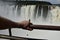 A butterfly sits on a tourist's arm against the backdrop of a waterfall. Puerto Iguazu, Argentina