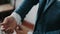 Buttoning a jacket hands close up. Stylish man in suit fastens buttons and straightens his jacket preparing to go out