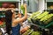 Buyer chooses grapes in the store. Girl is considering food in the market. Man buys healthy fruits